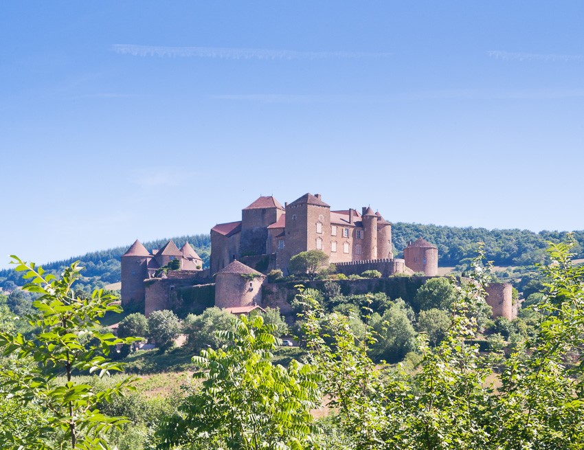 Photo of the medieval castle of Berze-le-Chatel in Burgundy, France with trees and light sky