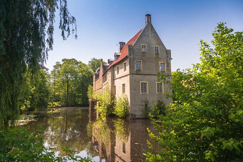 Photo of the moated Senden Castle with lake and green trees, North Rhine-Westphalia, Germany