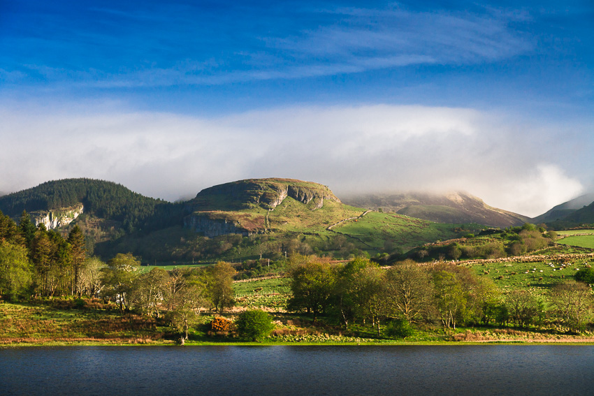 Landscape photo with green hills and mountains, lake and blue sky in Ireland